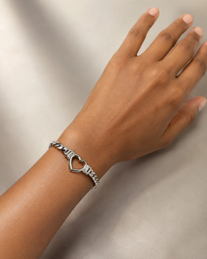 Elli Jewellery rhodium plated Cuban link bracelet featuring a central open heart charm worn on a model's wrist