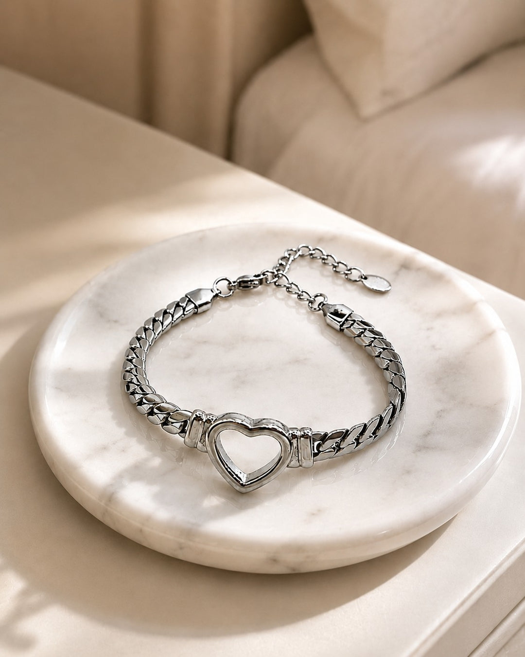 Elli Jewellery rhodium plated Cuban link bracelet featuring a central open heart charm on a marble display tray