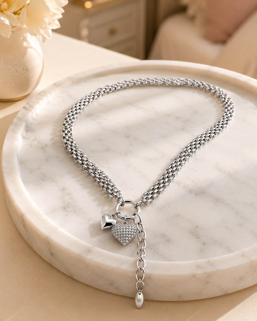 Elli Jewellery rhodium plated heart pendant necklace with a textured chain and double heart charms on a marble tray.