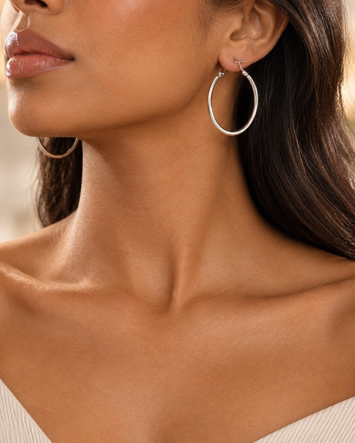Elli Jewellery classic smooth rhodium plated hoop earrings worn by a woman with long dark hair