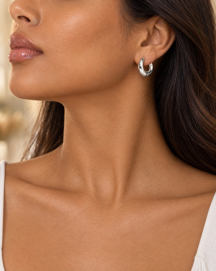 Elli Jewellery rhodium plated minimalist huggie hoop earrings worn on a woman's ear for a sleek modern look