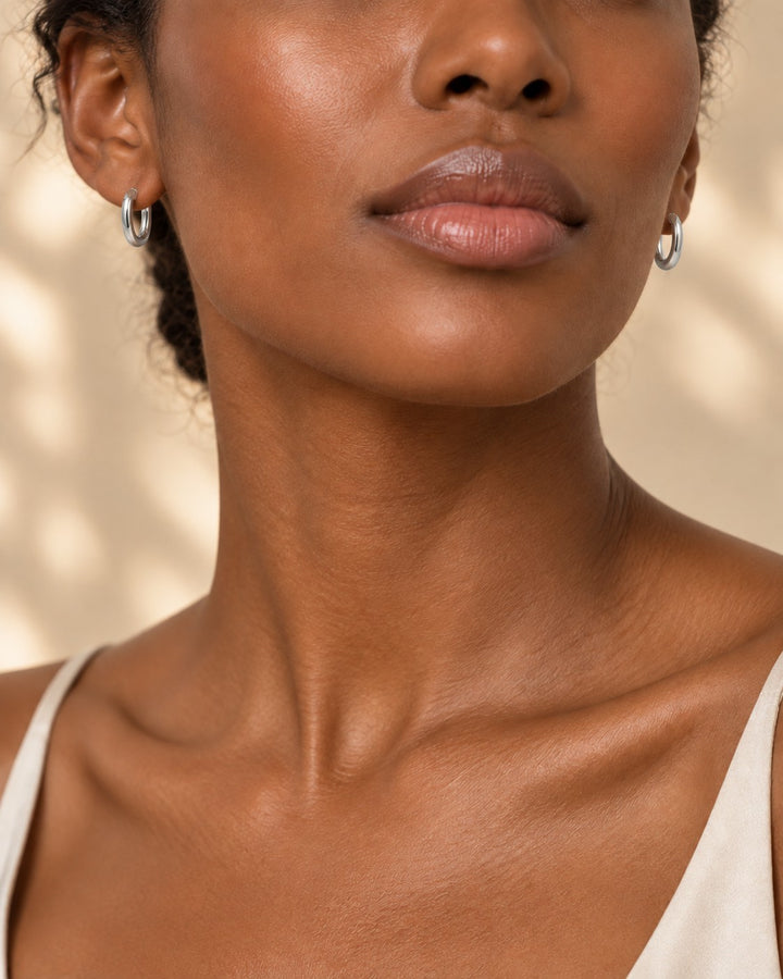 Elli Jewellery rhodium plated silver huggie hoop earrings worn by a woman with a minimalist aesthetic