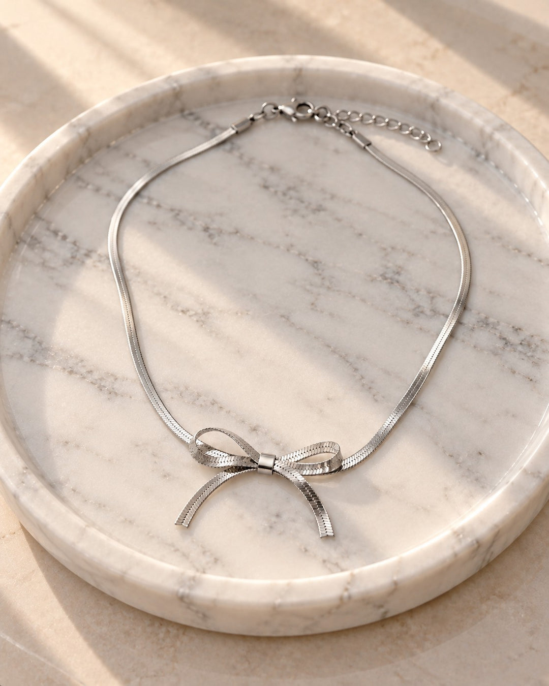 Elli Jewellery rhodium plated silver-tone snake chain necklace featuring a delicate sculptural bow knot design.