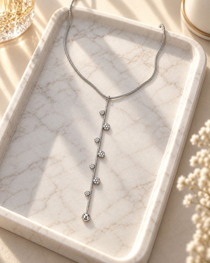 Elli Jewellery rhodium plated minimalist lariat necklace with delicate crystal-studded accents on a marble tray.