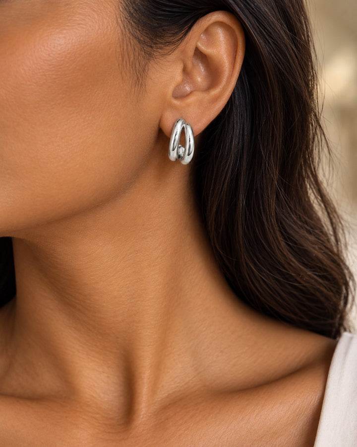 Elli Jewellery rhodium plated hollow C-shaped hoop earrings worn on a model, featuring a polished silver-tone finish.