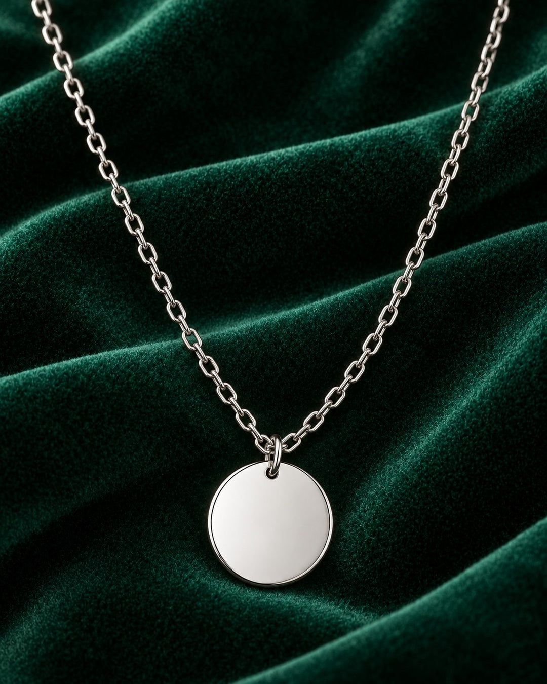 Elli Jewellery rhodium plated minimalist round pendant necklace on a dark green velvet background