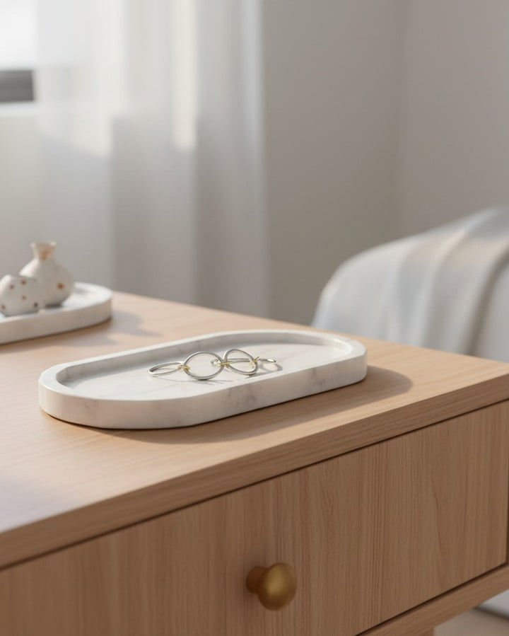 Elli Jewellery rhodium plated multilayer stacking rings resting on a white marble tray on a wooden bedside table.