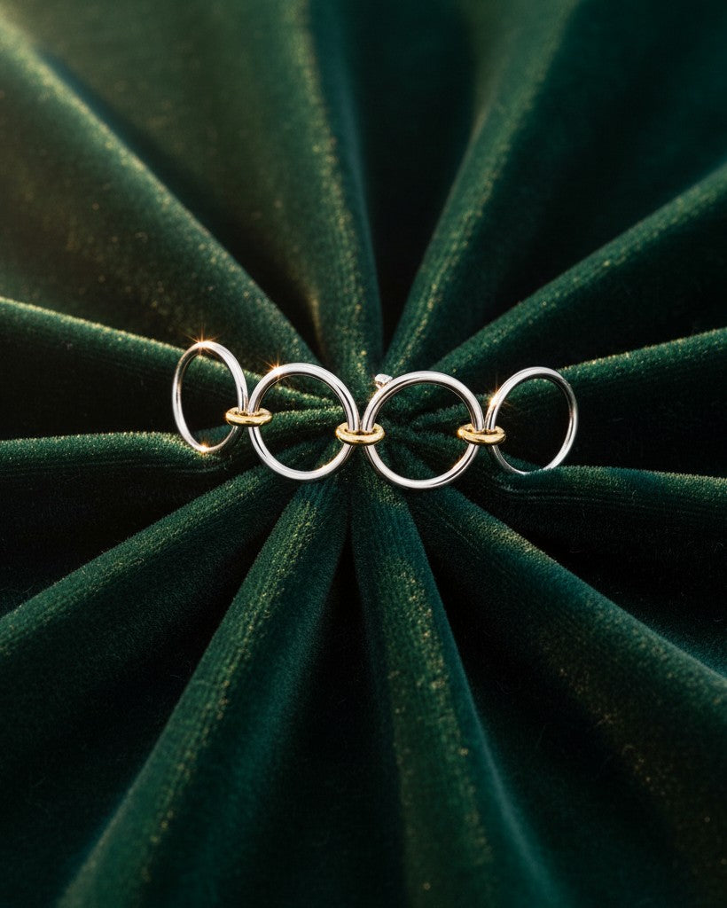 Elli Jewellery rhodium plated multilayer stacking rings with gold-tone accents on a dark green velvet background.