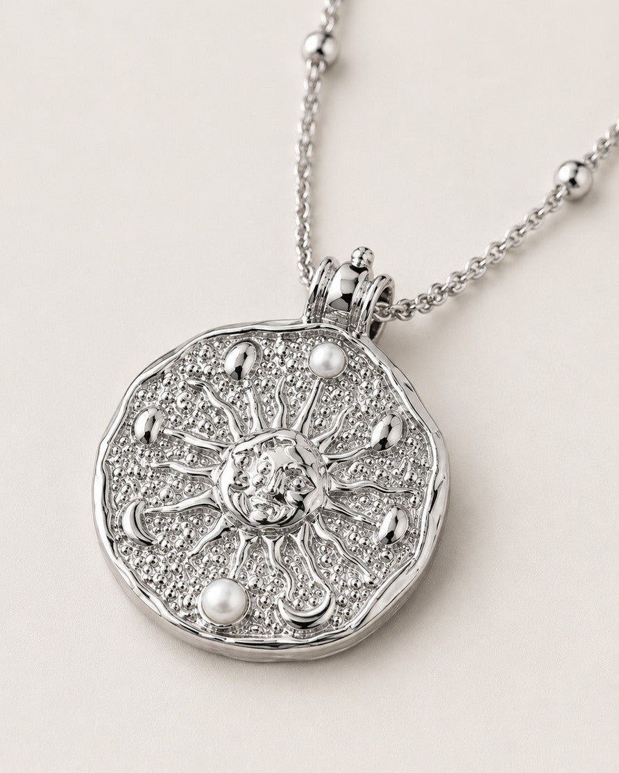 Elli Jewellery rhodium plated medallion necklace with a sun motif, ornate relief detailing, and pearl accents.