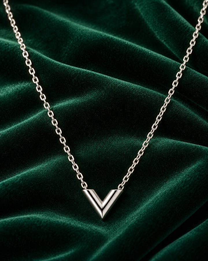 Elli Jewellery rhodium plated minimalist V-shaped necklace on a dark green velvet background