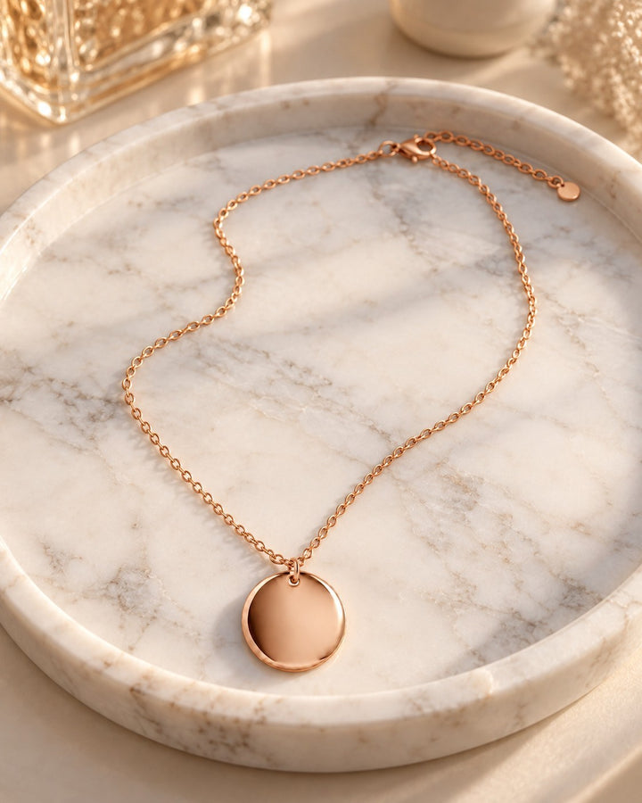 Elli Jewellery minimalist rose gold plated pendant necklace on a marble tray, featuring a simple round disc charm.