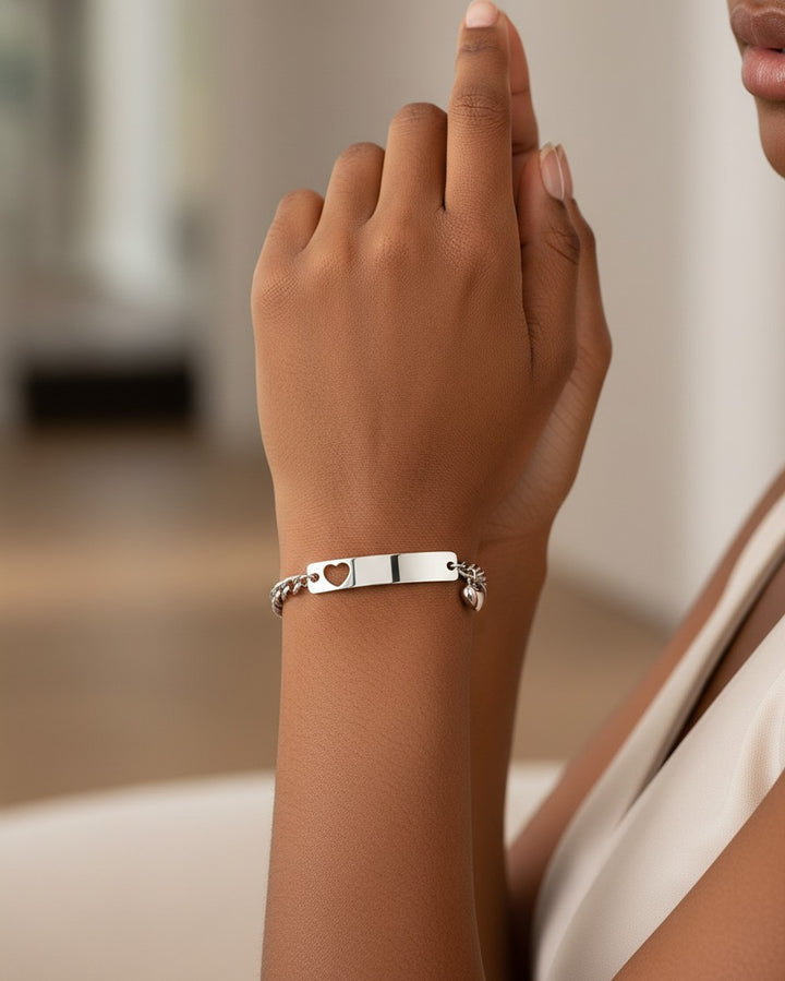 Elli Jewellery silver plated heart ID tag charm bracelet worn on a woman's wrist, featuring a delicate chain.