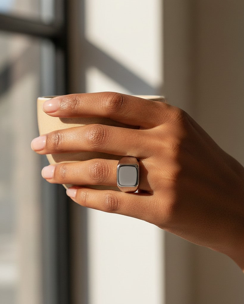 Elli Jewellery silver stainless steel signet ring with a polished finish worn on a hand holding a ceramic cup.