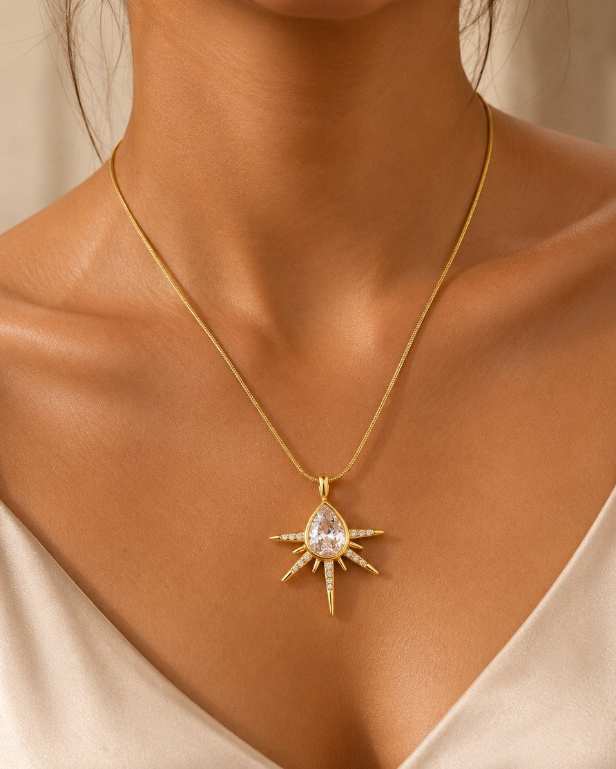 Elli Jewellery gold plated starburst pendant necklace featuring a central pear-shaped crystal and pavé stone accents.