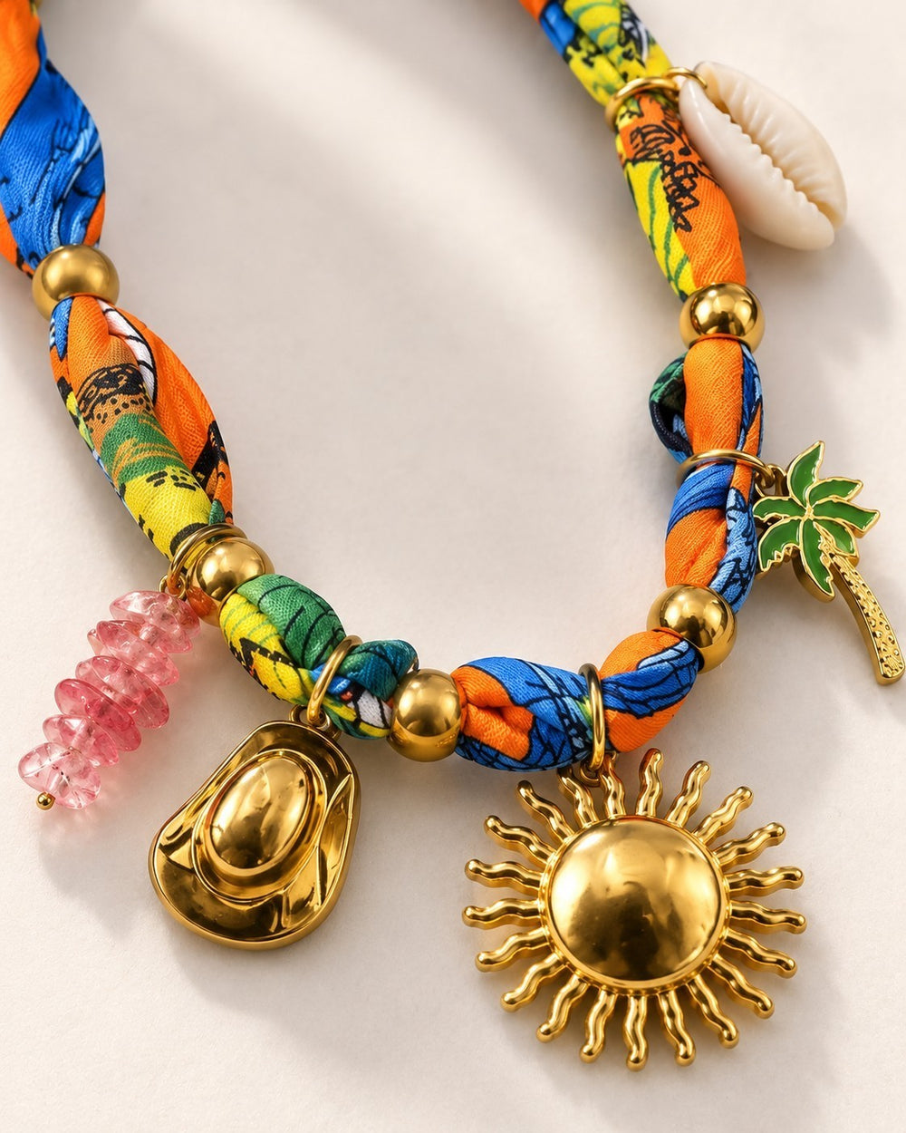 Elli Jewellery vibrant charm necklace featuring a colorful silk scarf band, gold sunflower, cowboy hat, and shell charms
