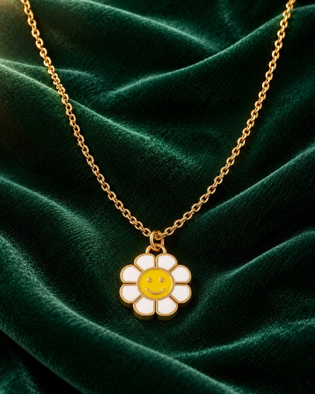 Elli Jewellery gold plated necklace featuring a white and yellow sunflower smiley face pendant on a velvet background.