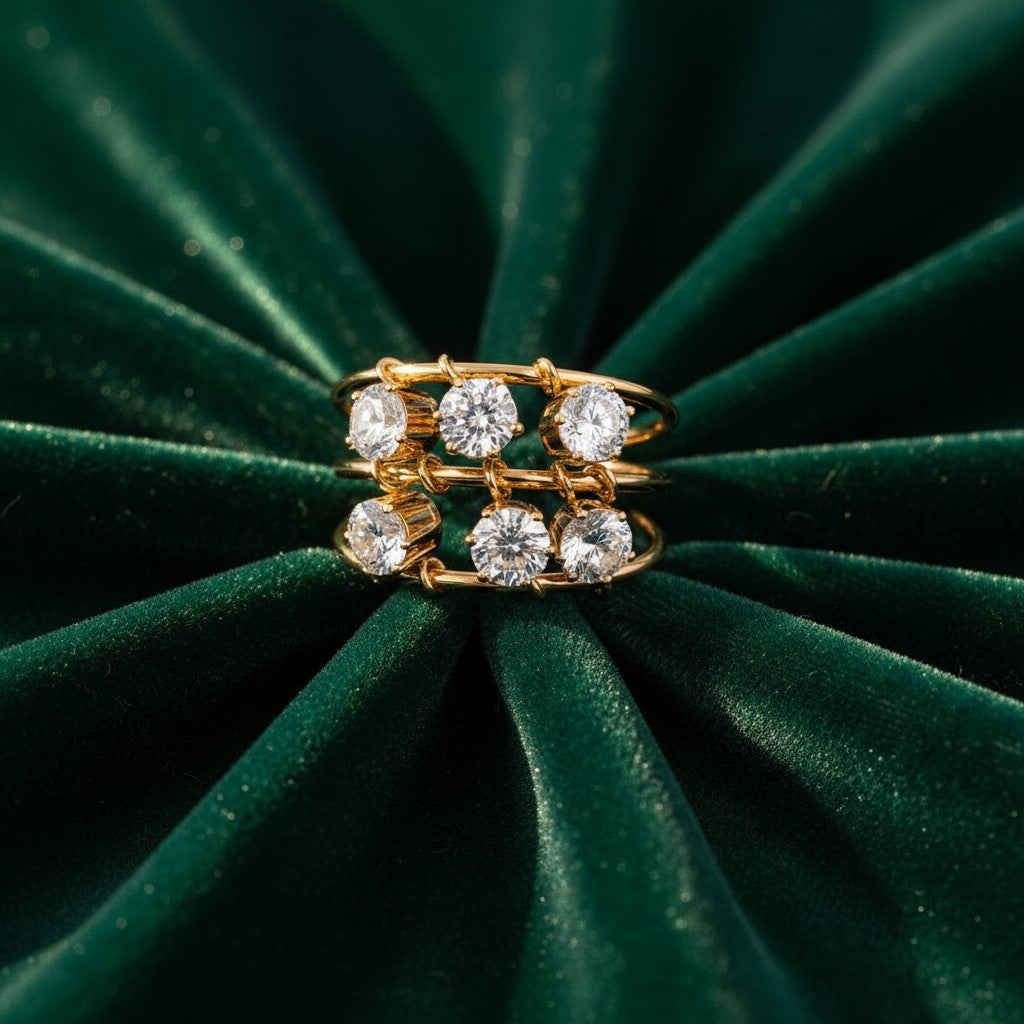 Elli Jewellery triple band gold plated ring with six clear cubic zirconia stones on a dark green velvet background