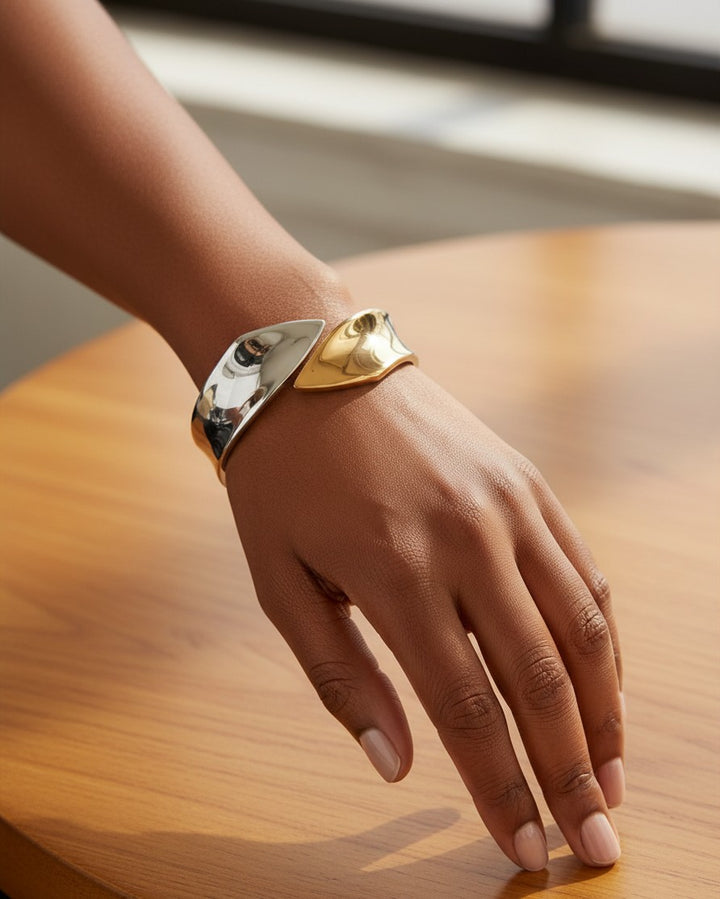 Elli Jewellery two-tone bangle bracelet in rose gold and silver, featuring a sleek sculptural design on a wrist.