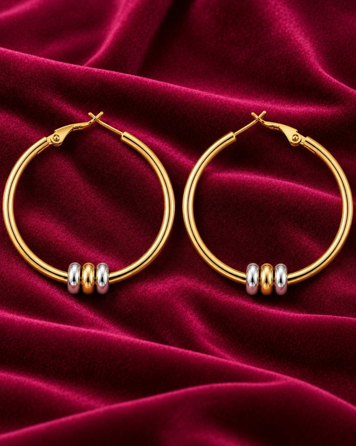 Elli Jewellery two-tone hoop earrings featuring gold-plated hoops with rhodium and gold-tone beads on velvet fabric.