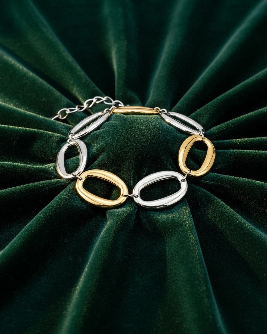 Elli Jewellery two-tone chunky chain link bracelet with alternating gold and silver oval links on green velvet.