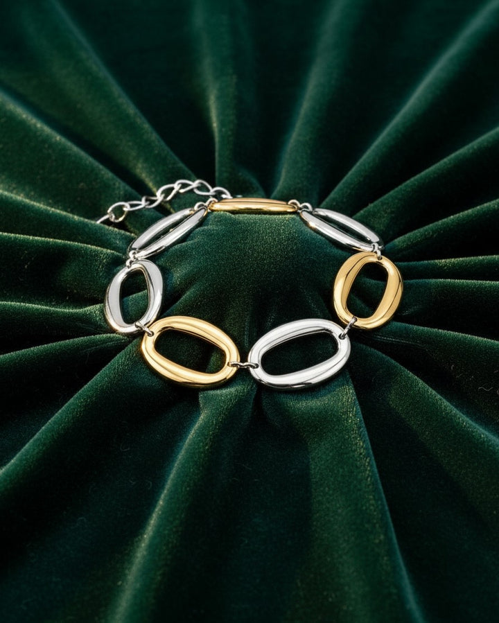 Elli Jewellery two-tone chunky chain link bracelet with alternating gold and silver oval links on green velvet.