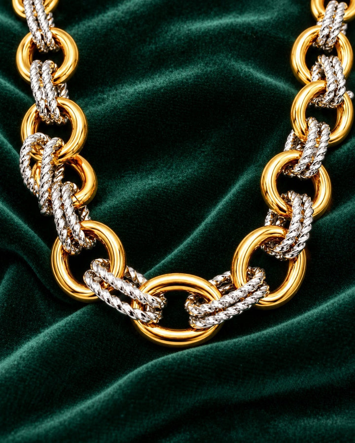 Elli Jewellery gold plated two-tone chunky chain necklace with mixed metal links on a green velvet background.