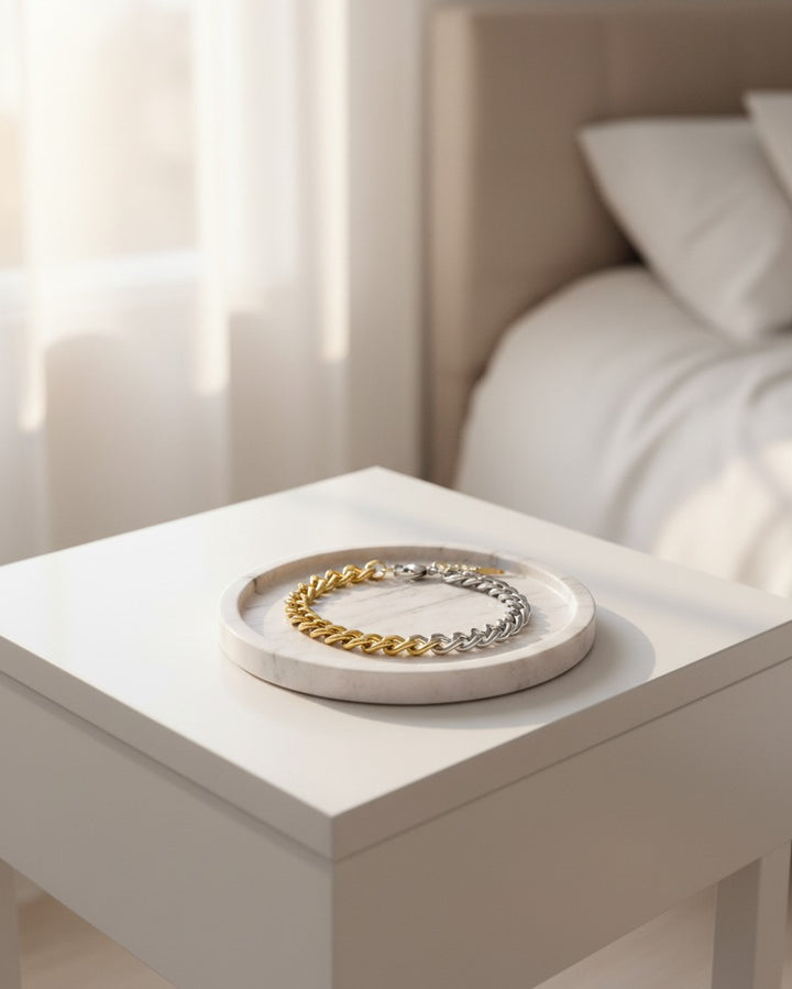 Elli Jewellery two-tone Cuban link chain bracelet in gold and silver resting on a marble tray in a bright room.