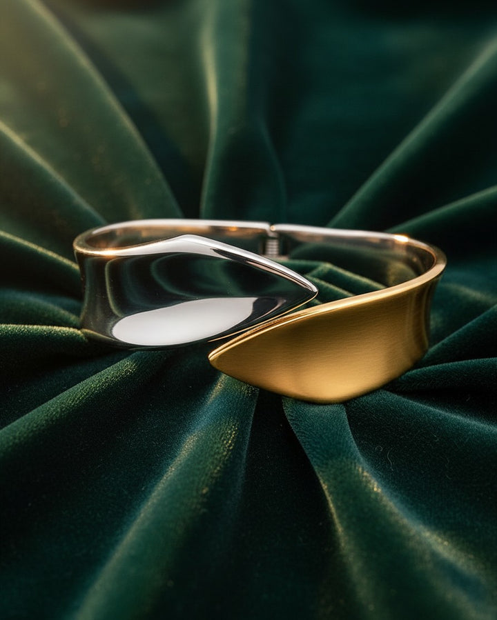 Elli Jewellery two-tone rose gold and silver fusion bangle bracelet with a sleek sculptural design on green velvet.