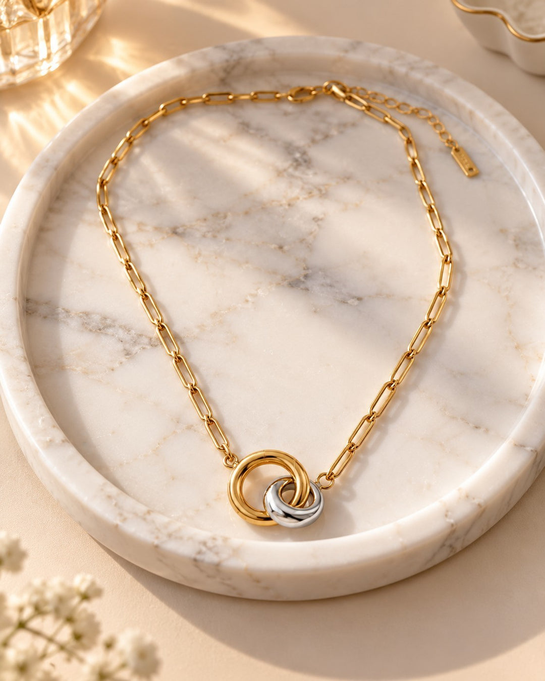 Elli Jewellery two-tone geometric link chain necklace featuring interlocking gold and silver rings on a marble tray.