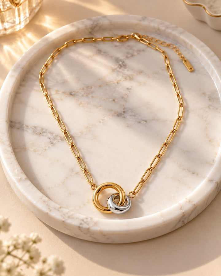 Elli Jewellery two-tone geometric link chain necklace featuring interlocking gold and silver rings on a marble tray.