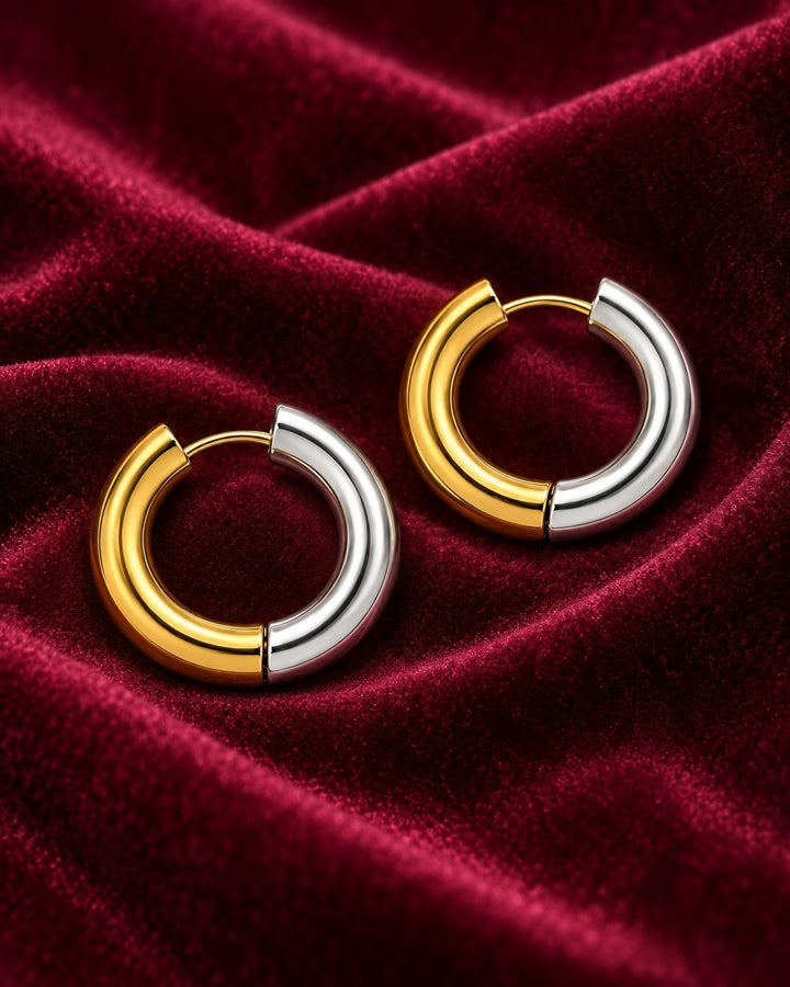 Elli Jewellery two-tone 18mm huggie hoop earrings featuring a polished gold and silver plated finish on red velvet.