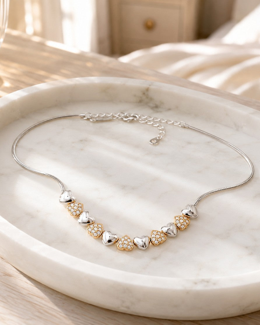 Elli Jewellery two-tone heart charm necklace with rhodium and gold plated finishes and pavé crystals on marble tray