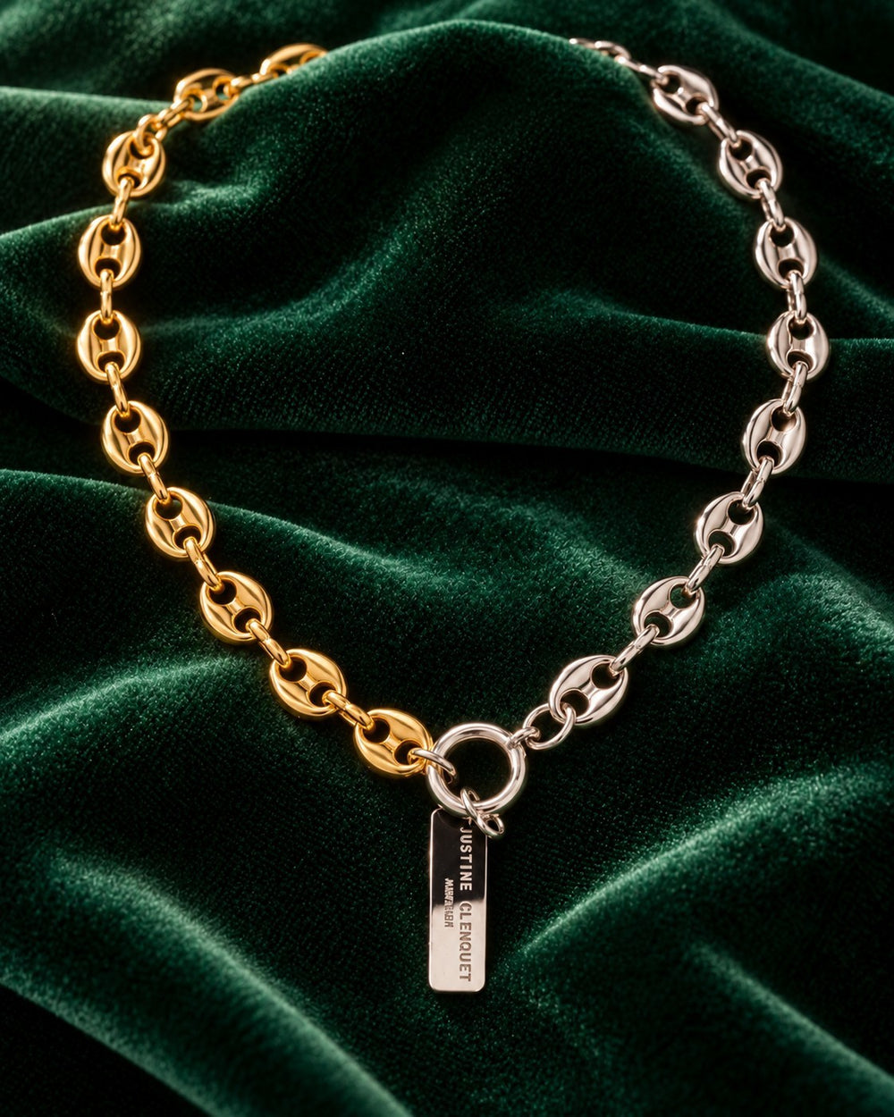Elli Jewellery two-tone gold and silver plated oval link chain necklace with a toggle clasp on green velvet fabric.