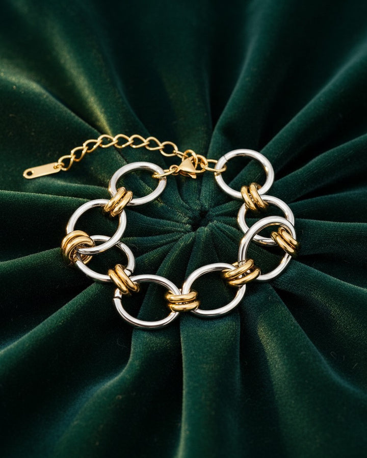 Elli Jewellery two-tone ribbed link bracelet featuring alternating gold and silver plated circular links on green velvet