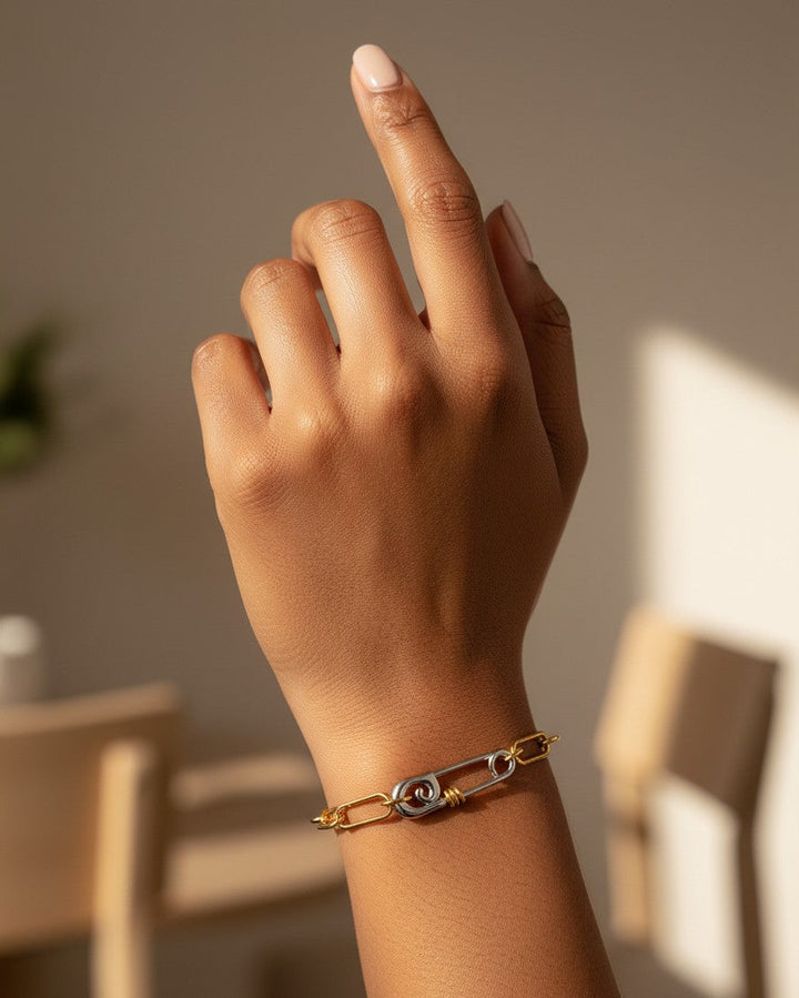 Elli Jewellery two-tone gold and silver chain link bracelet with a safety pin clasp worn on a model's wrist.