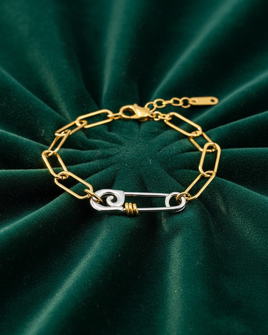 Elli Jewellery two-tone gold and silver chain link bracelet featuring a unique safety pin clasp on green velvet.
