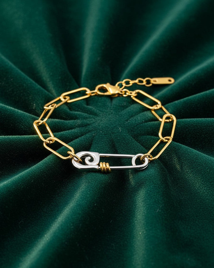 Elli Jewellery two-tone gold and silver chain link bracelet featuring a unique safety pin clasp on green velvet.