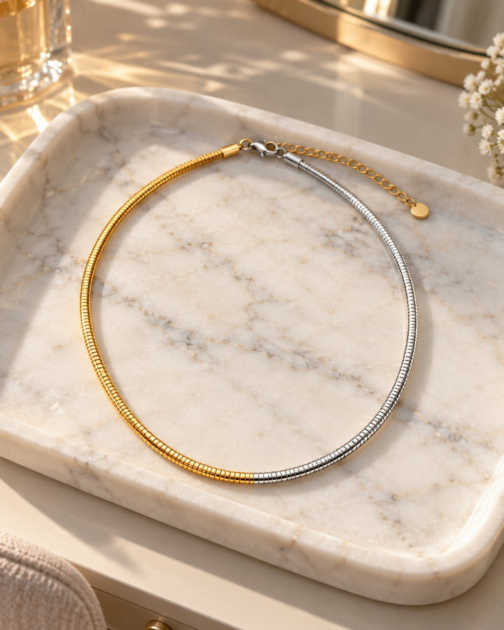 Elli Jewellery two-tone snake chain necklace in gold and silver plating resting on a marble tray.