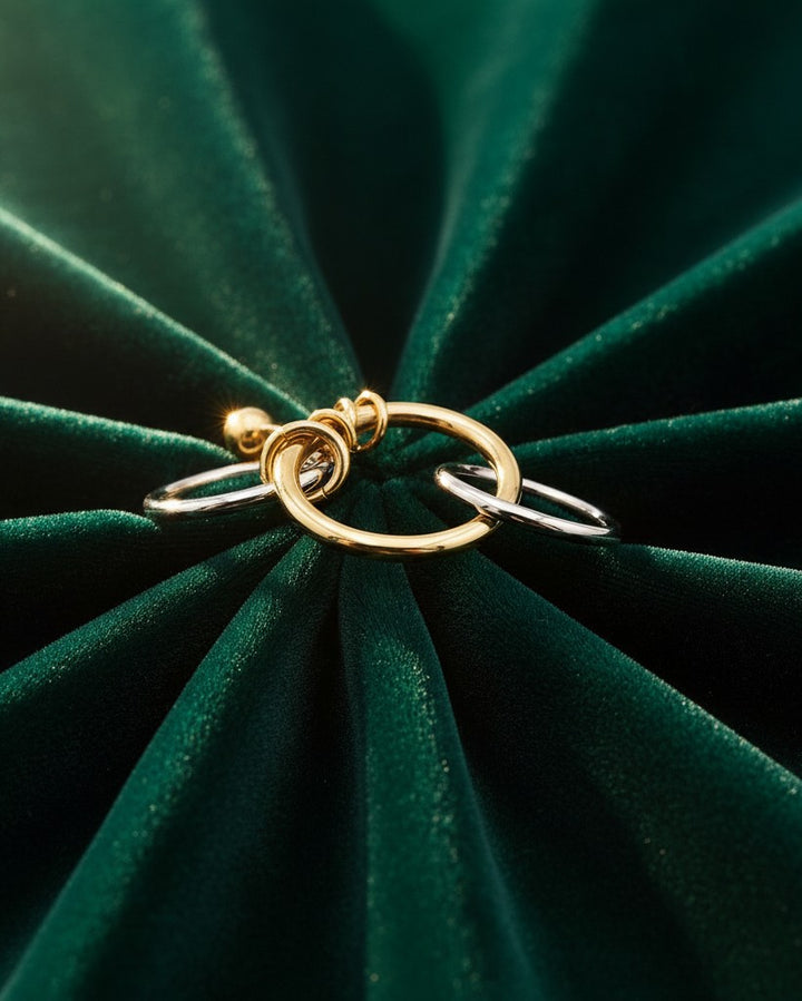 Elli Jewellery two-tone stacked ring set featuring three layered gold and silver bands on a dark green velvet background.